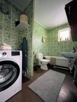 Badrum med toalett, badkar, handfat och tvättmaskin