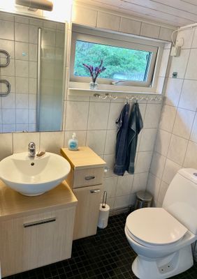 Fristående badrum med dusch och tvättmaskin. Fem steg från gästhuset.