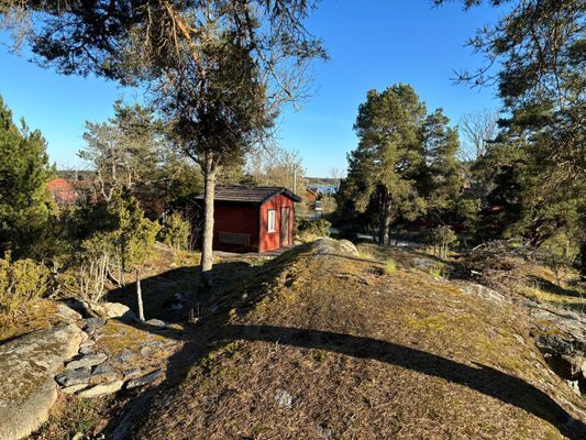 Utsikt från altan i söderläge med gäststuga och havsglimt