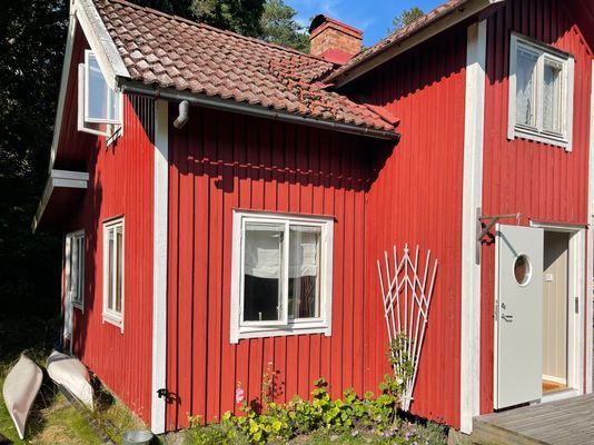 Rött stenhuggartorp nära hav och skog