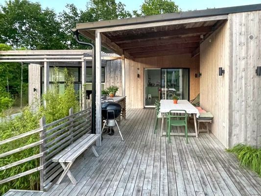 Stor uteplats med matplats under tak och grill för sommarkvällar