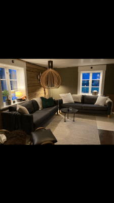 Vardagsrummet på nedervåningen med 2 soffor och öppen spis. TV finns också.