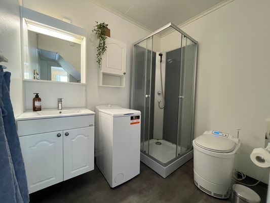 Badrum med dusch och modern förbränningstoalett.