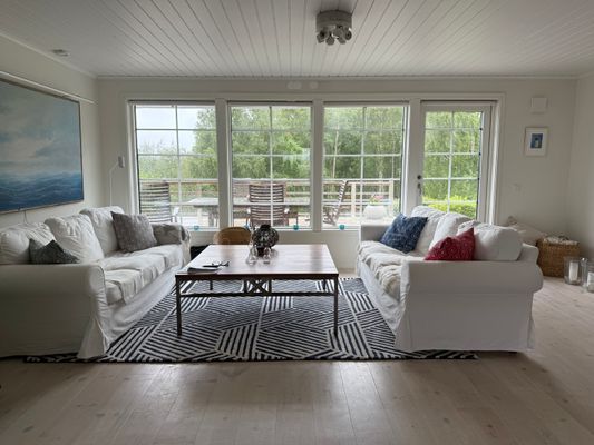 Vardagsrum med stora fönster och dörr mot altanen