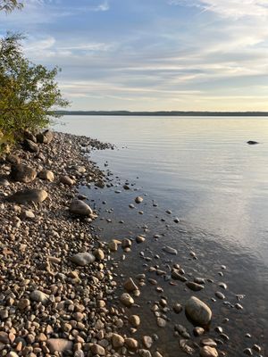 Stenstranden vid Unden som nås via en skogsstig. Det går att hitta en plats med lite mera sand, men ett tips är att ha badtofflor på och vara försiktiga så att ni inte halkar.