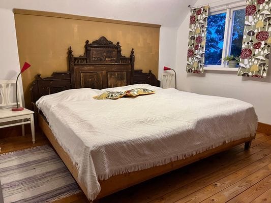 Sovrum med dubbelsäng (mått 2 x 105 x 200 cm) på ovanvåningen, med vy mot byn och ljudet av porlande vatten från Lillån.