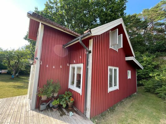 Rött stenhuggartorp nära hav och skog