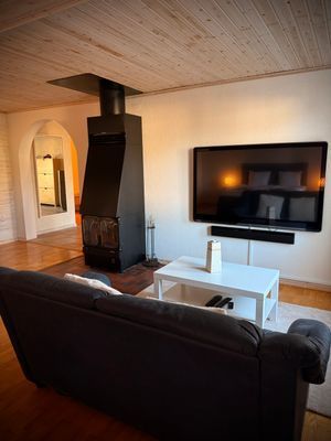 Öppen planlösning med braskamin för sköna höst och vinterkvällar. Här finns TV med tillgång till Netflix, en bäddsoffa och en varm, inbjudande atmosfär med trägolv och träpanel i taket.