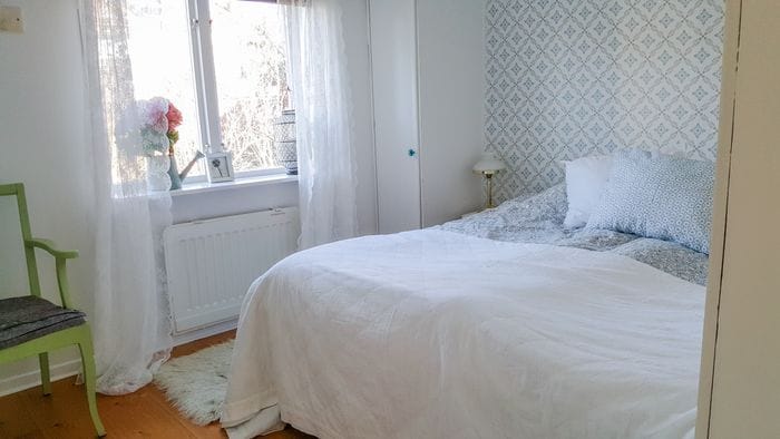 Sovrum med dubbelsäng, garderob, krokar och förvaringslådor under sängen