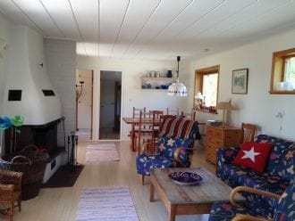Allrum med öppen spis och soffgrupp i förgrunden, matplats i bakgrunden
