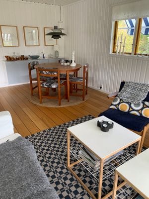 I stugans största rum finns soffa vid teven och matplats. Det finns en iläggsskiva till bordet.