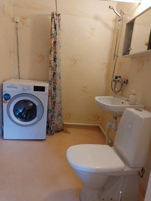 Enkelt badrum med toalett, dusch och tvättmaskin.