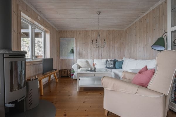 Vardagsrumsdel i storstugan med täljstenskamin, TV, spel, pussel och böcker.