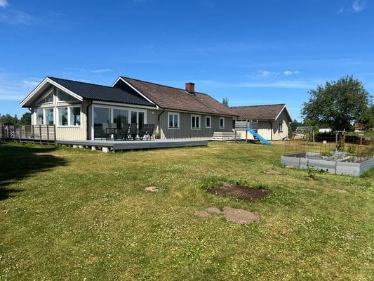 Baksidan av huset med uteplats, lekplats och odling.