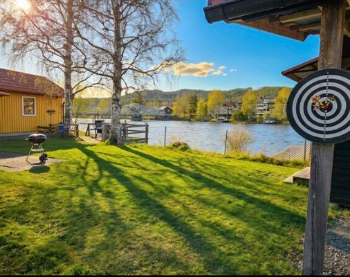 Stor trädgård vid älven med terrass, grill och utomhusspel – perfekt för hela familjen