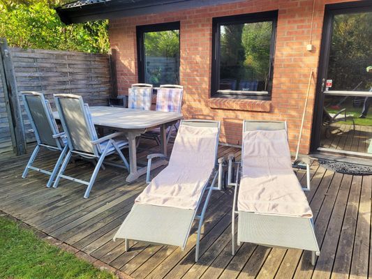 Terrass med bord och stolar samt solstolar