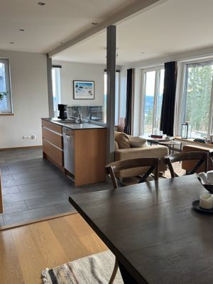 Modernt och luftigt vardagsrum i anslutning till socialt kök och matplats.